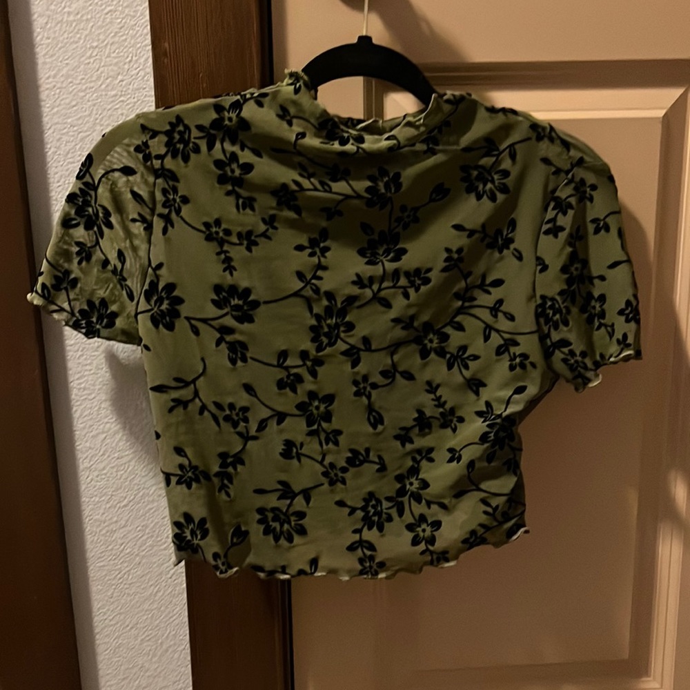 Shear green crop top with black flowers and a black v-neck tank top underneath.